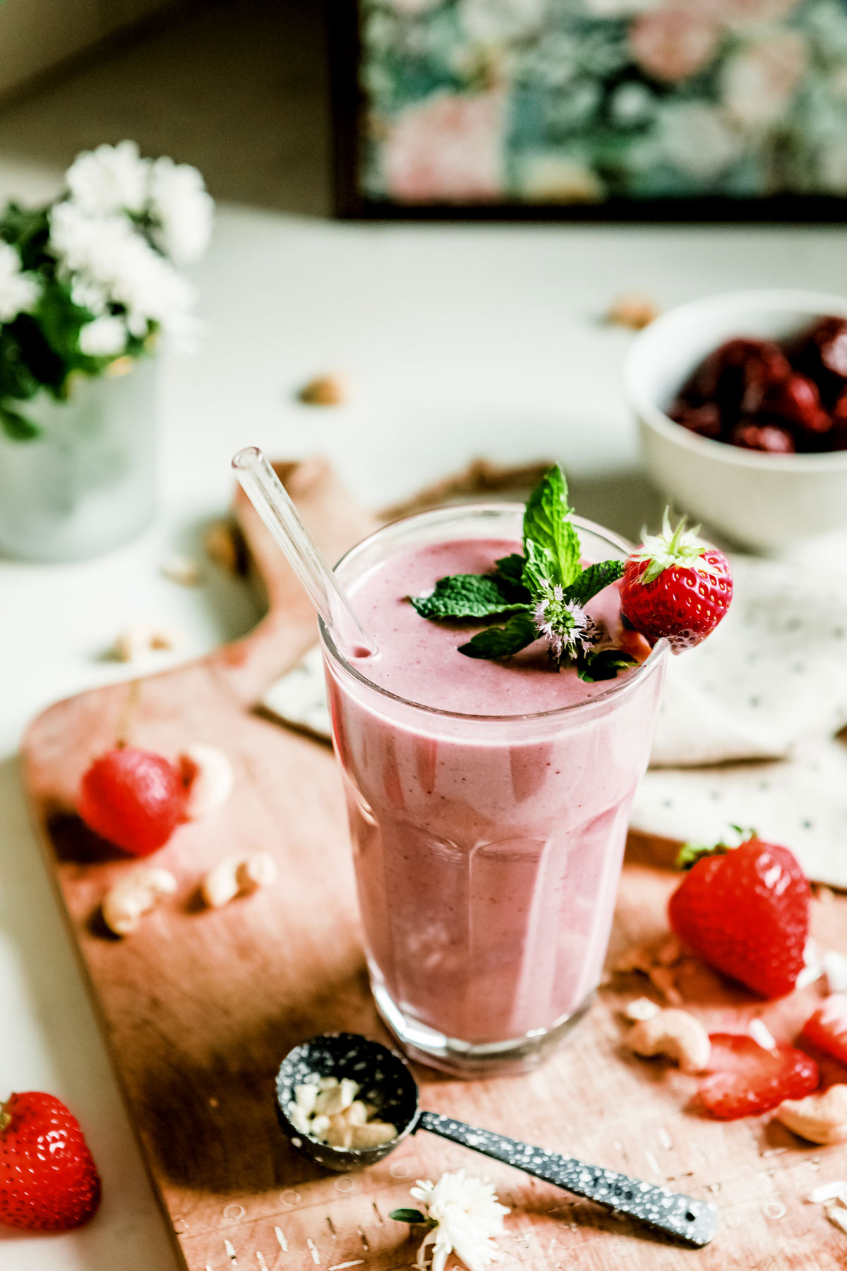 glass of strawberry smoothie on counter with fresh strawberries
