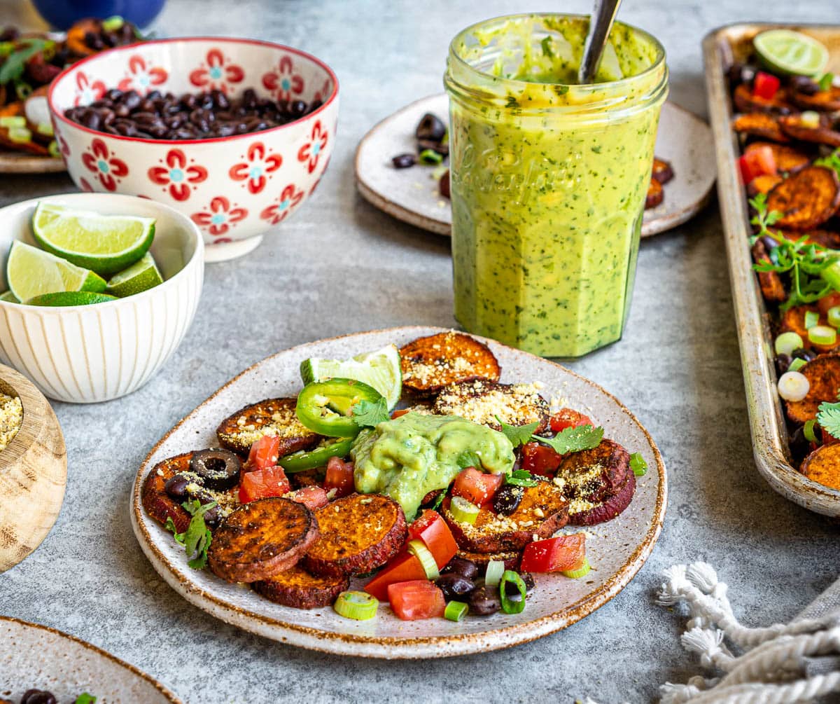 loaded sweet potato nachos and a glass jar of avocado crema.