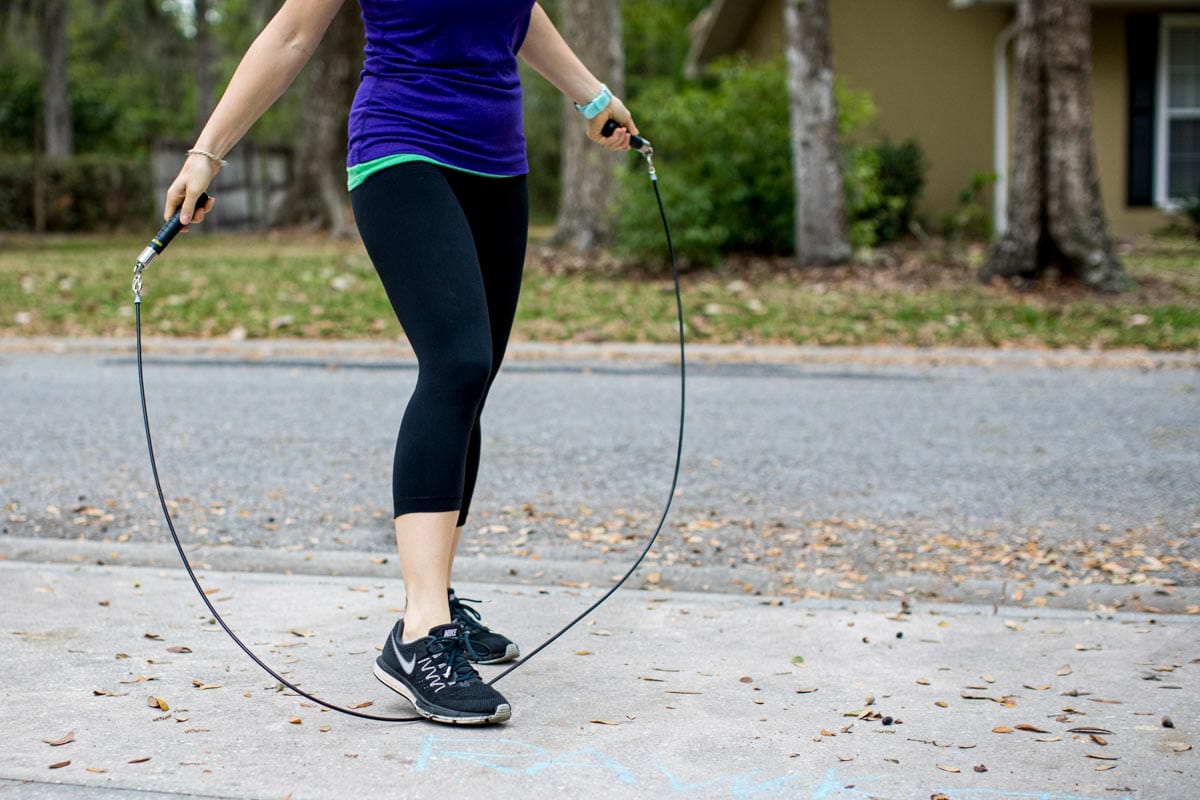 white woman working out using a jump rope in a neighborhood.