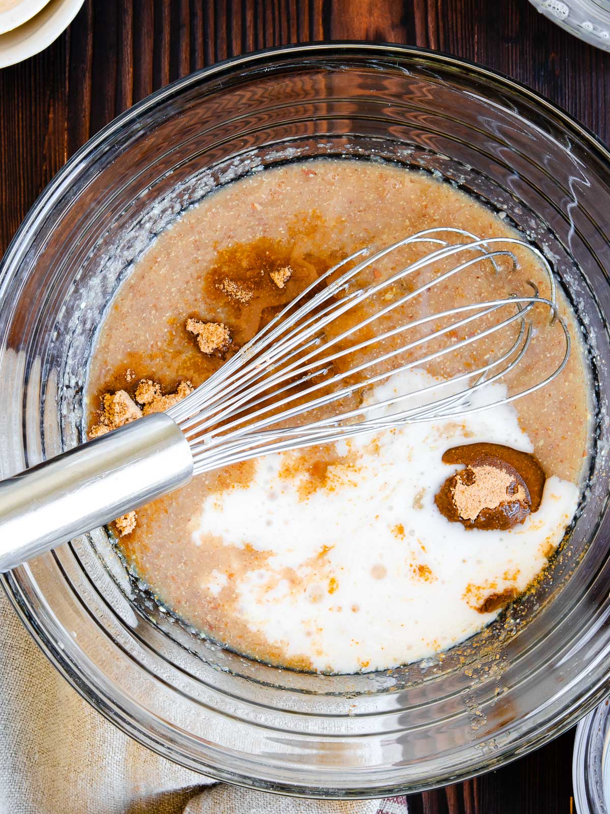 glass bowl with several mixed ingredients for zucchini bread recipe and a whisk.