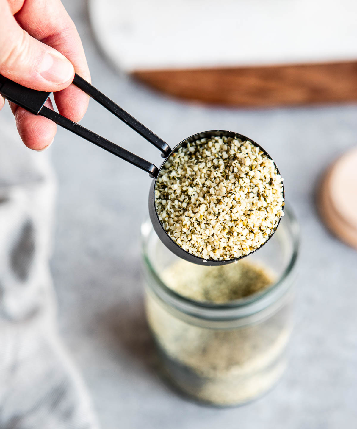 a black measuring cup with a scoop of hemp hearts in it.