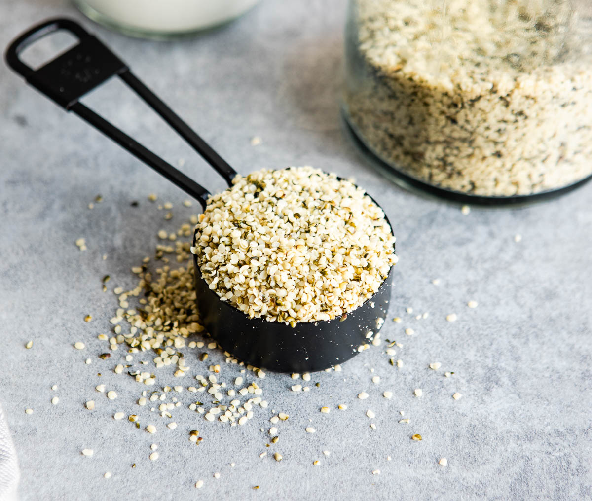 a black measuring cup with a scoop of hemp hearts in it.