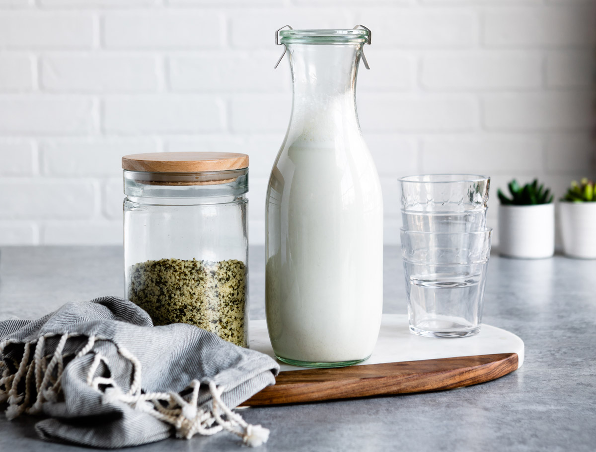 Hemp milk in a glass jar with hemp seeds next to it.