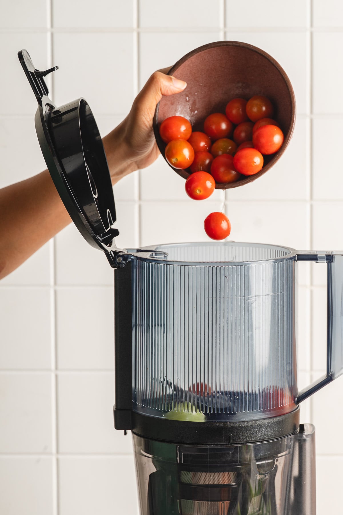 Adding cherry tomatoes in a juicer