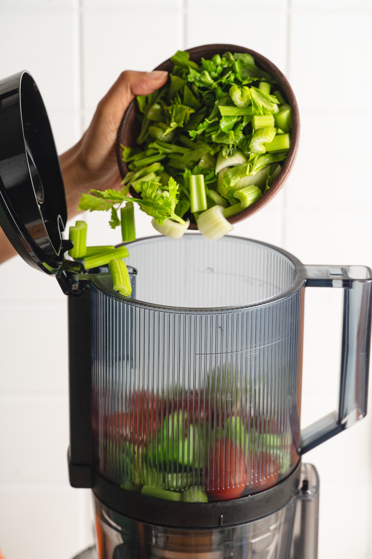 Adding chopped celery and other vegetables in the juicer