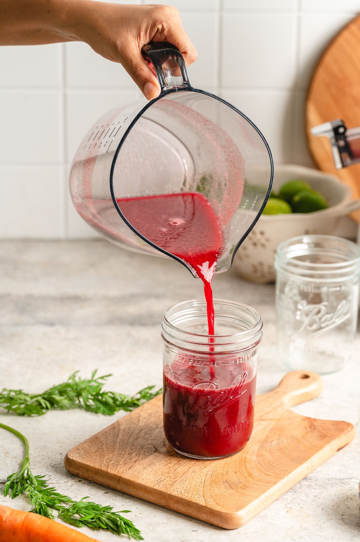 Pouring fresh homemade V8 juice into a mason jar