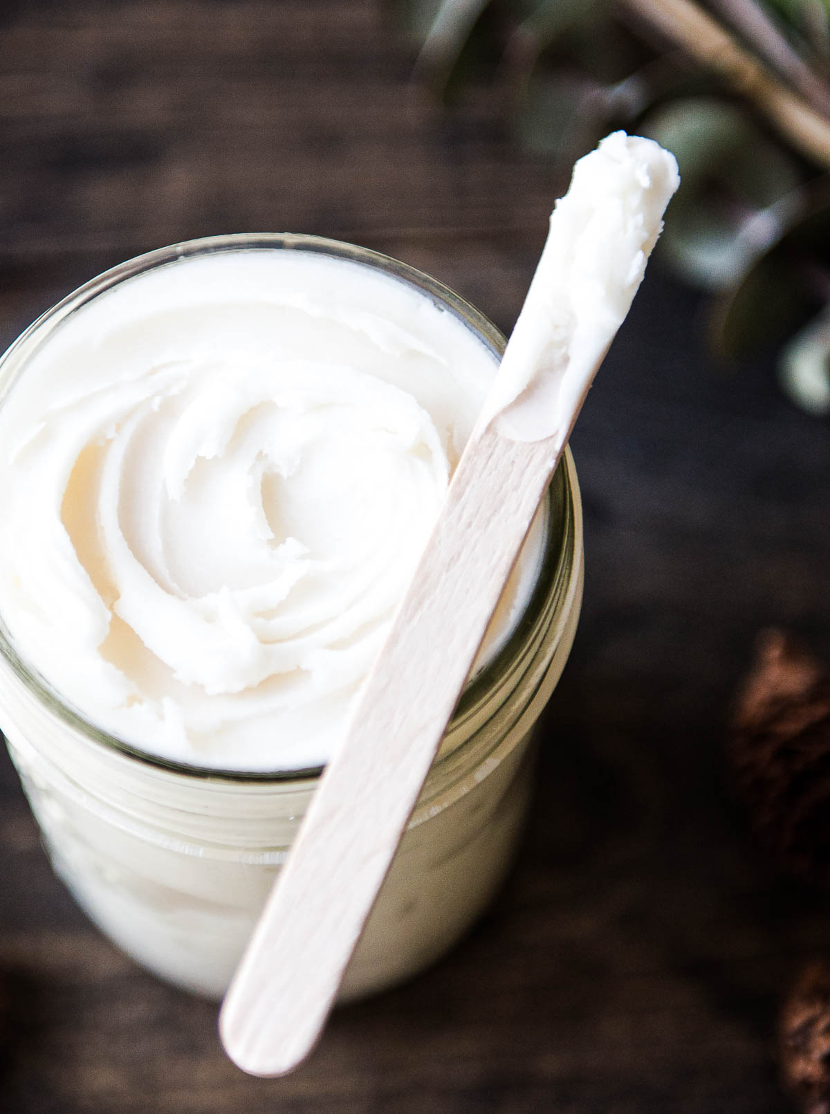 glass jar full of natural deodorant with a wooden popsicle stick applicator.