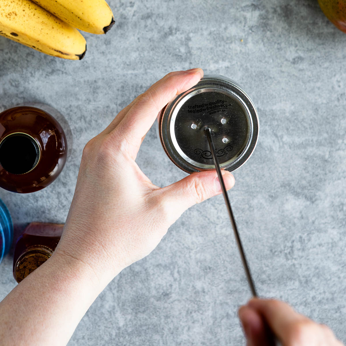 Poking holes in a mason jar lid with a metal skewer
