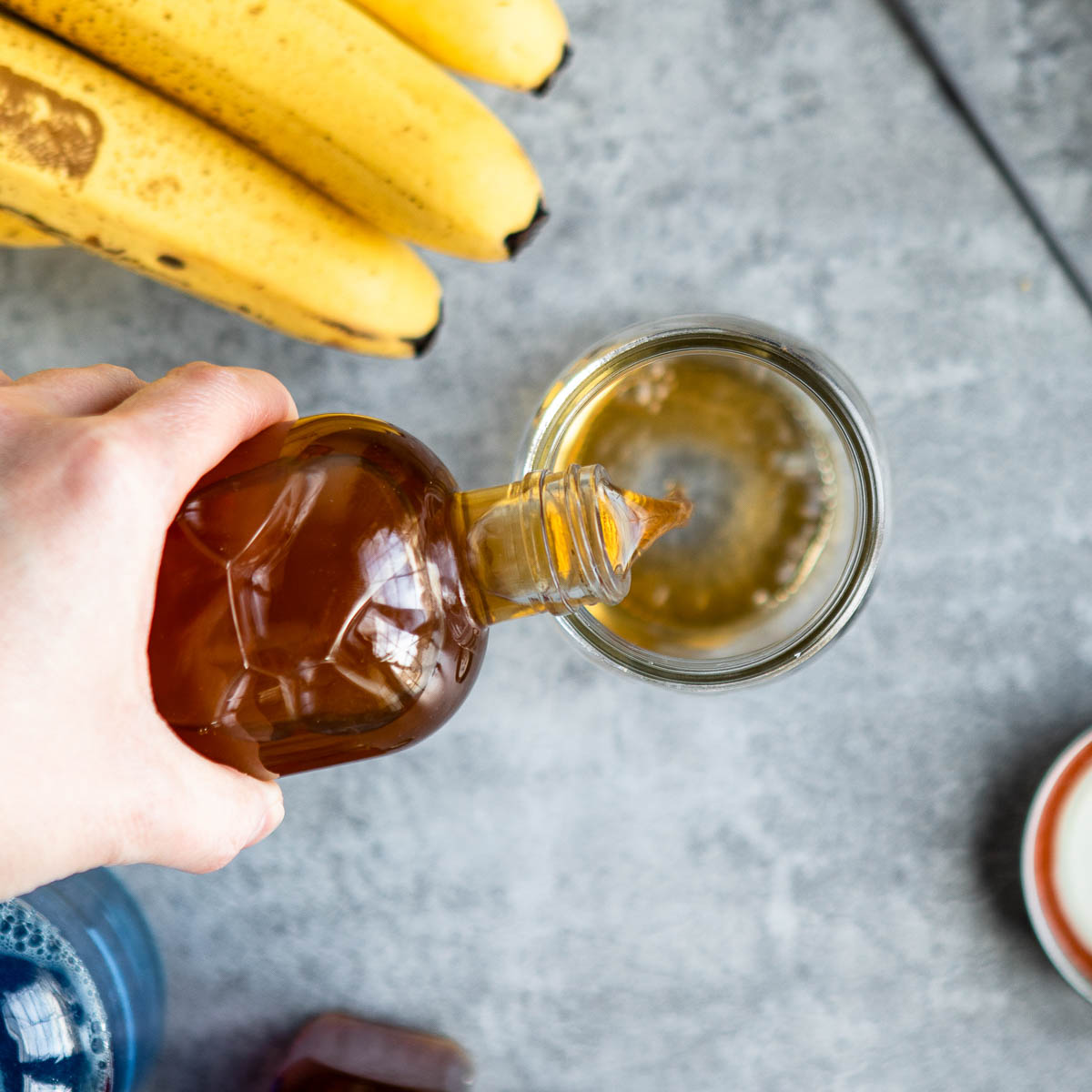 Pouring apple cider vinegar into a glass jar