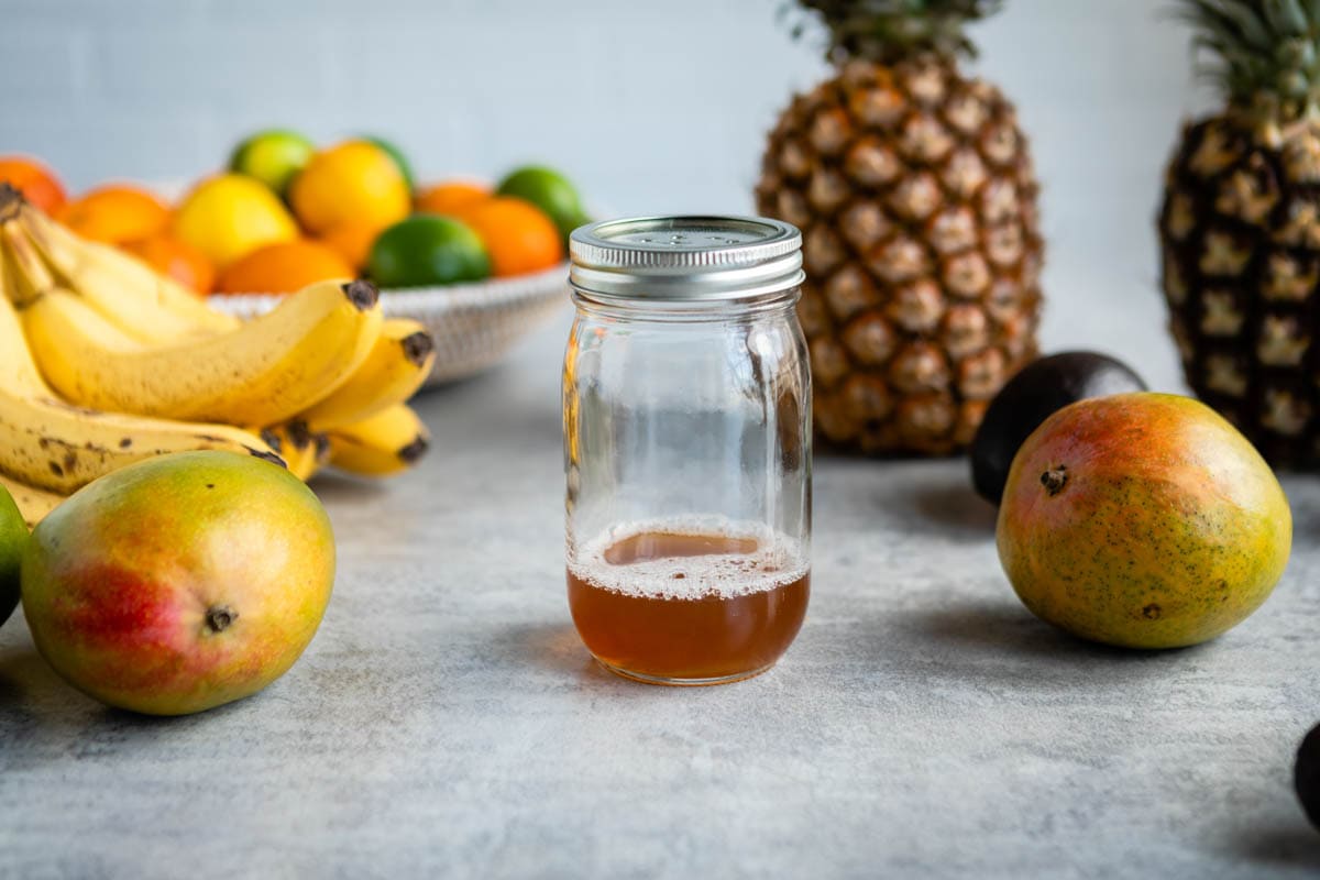 homemade fruit fly trap with fresh fruit all around it