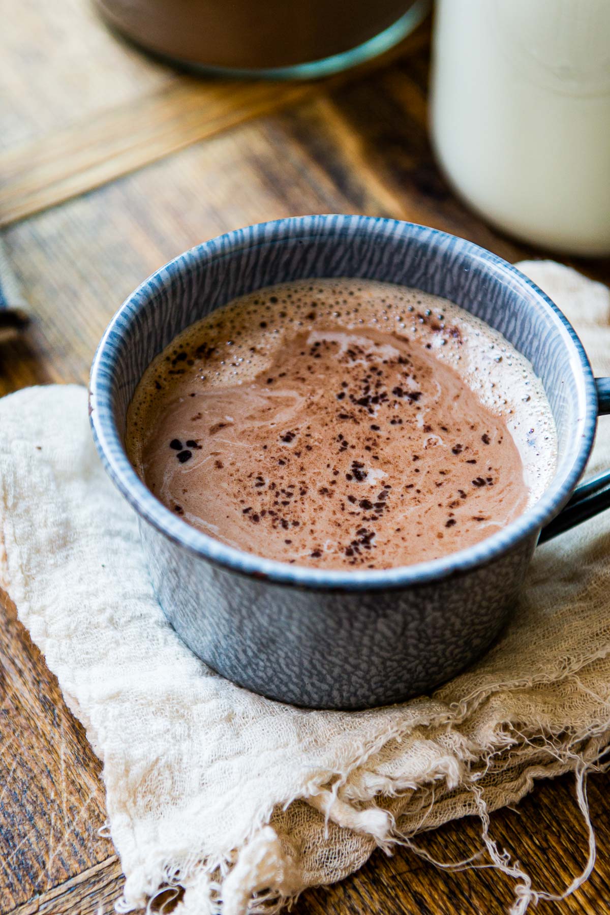 A blue mug filled with rich homemade hot chocolate placed on a woodgrain countertop.