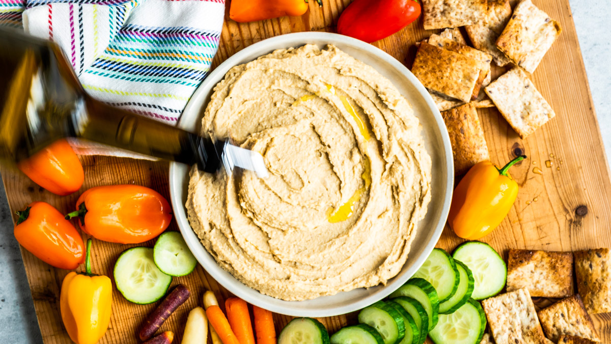 homemade hummus recipe on table with fresh cut vegetables