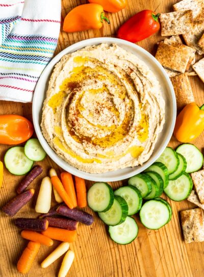Bowl of homemade hummus surrounded by vegetables.
