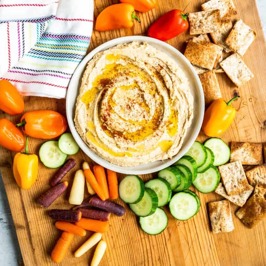 Bowl of homemade hummus surrounded by vegetables.