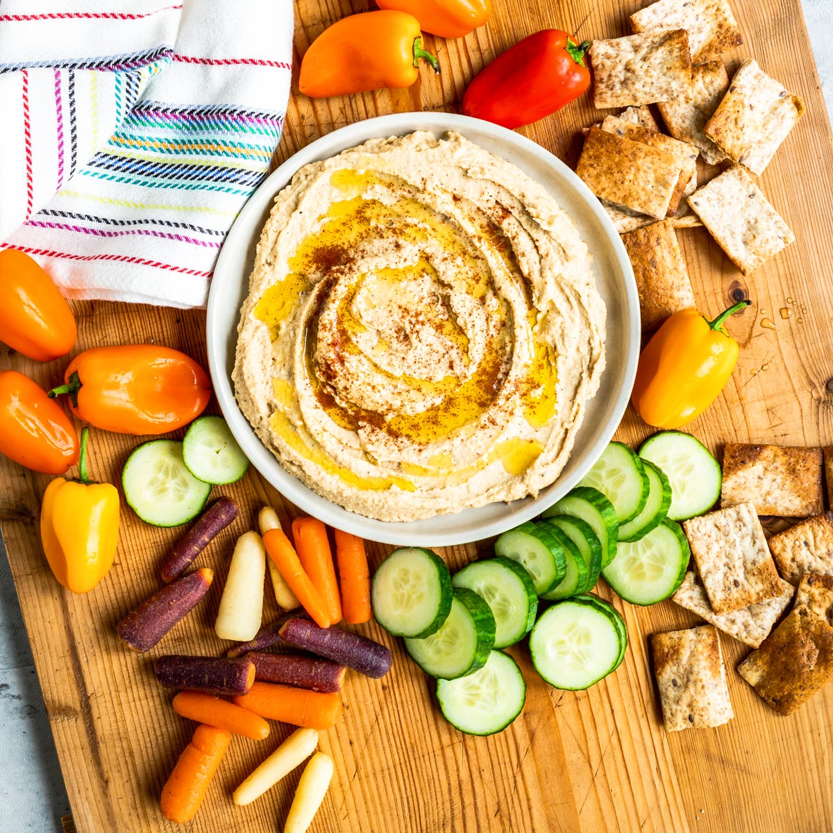 Bowl of homemade hummus surrounded by vegetables.
