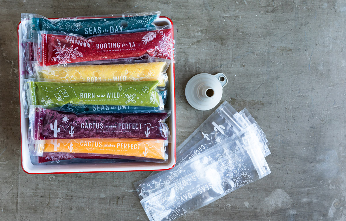 Gray funnel, popsicle sleeves and a red tray full of colorful ice pops.