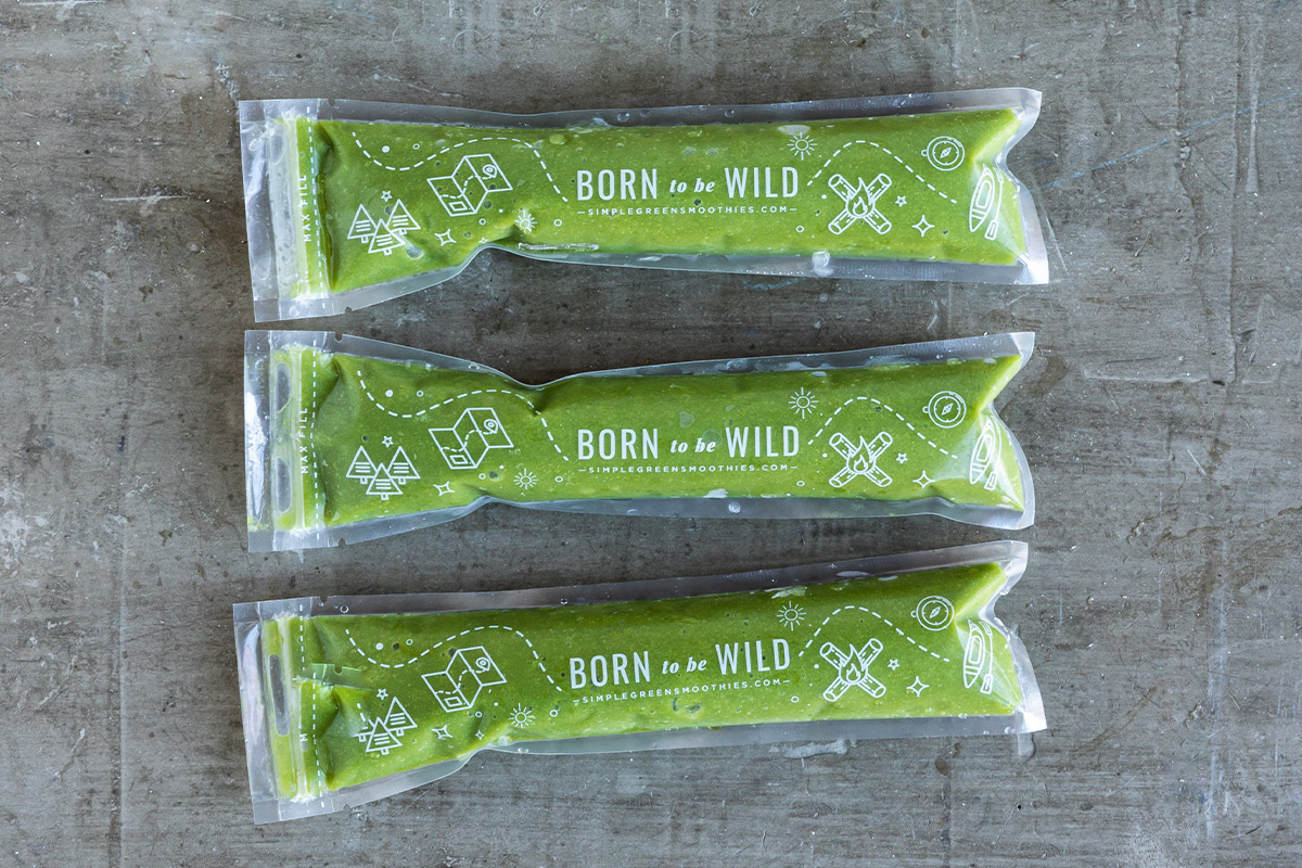 Three green homemade ice pops stacked on gray countertop.
