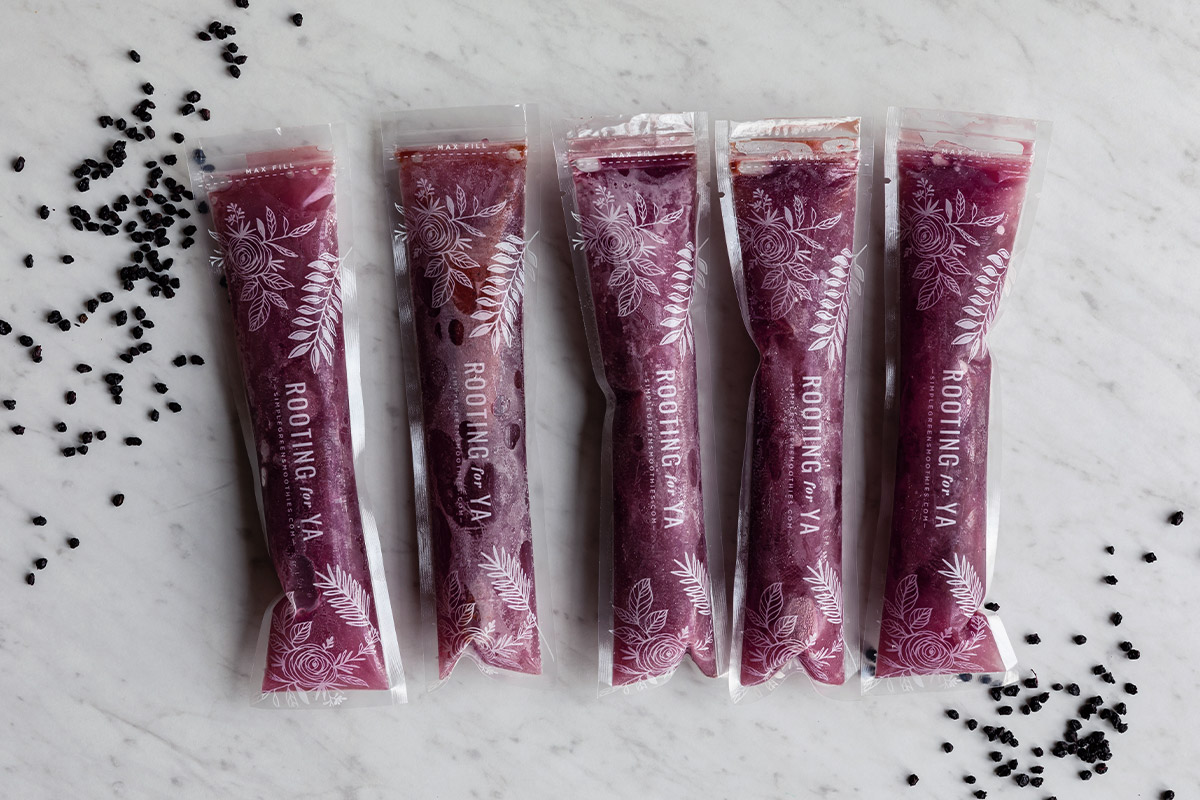 Purple ice pops in a row with elderberry flowers.