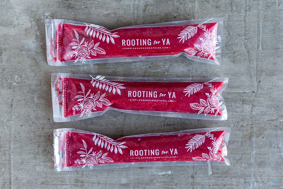 Three red homemade ice pops on concrete counter.