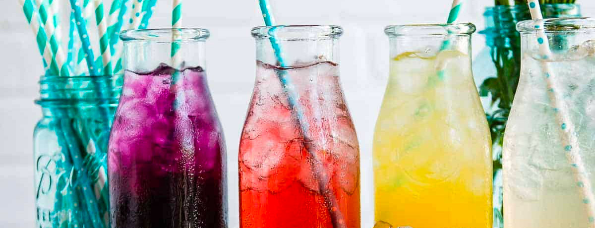 four Italian sodas in jars with straws—purple, red, yellow, and clear