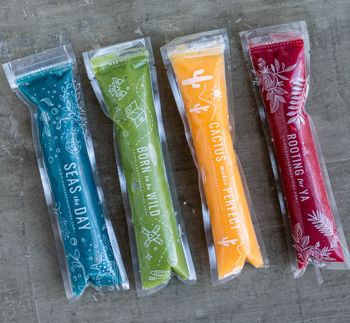 4 plastic sleeves filled with healthy homemade popsicles in blue, green, yellow and red.