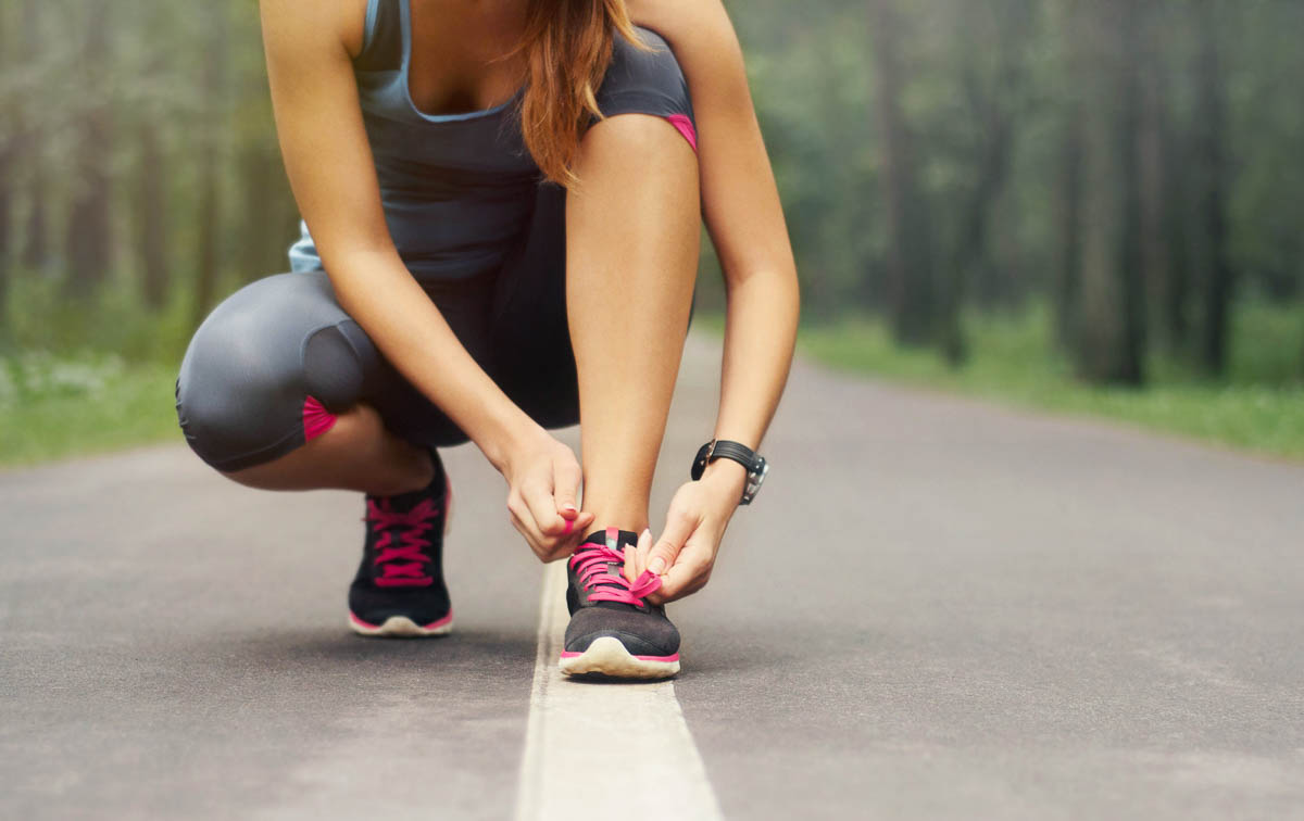 White female tying her pink laced sneakers after having a homemade protein powder recipe.