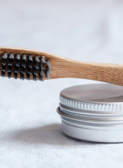 A wooden toothbrush resting on top of a metal container.