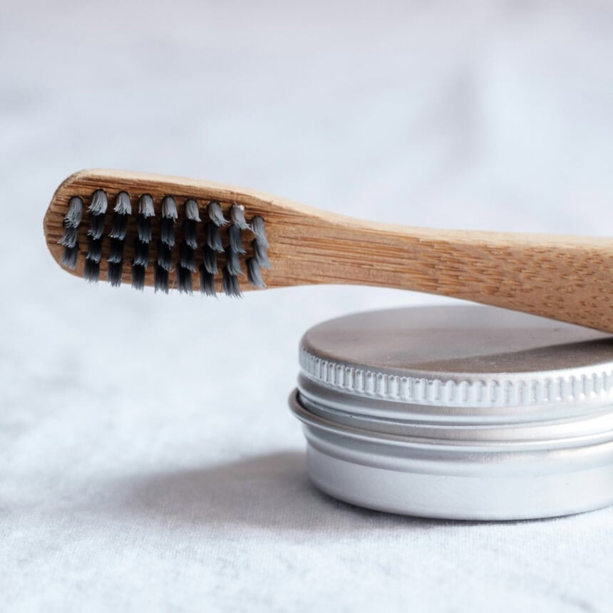A wooden toothbrush resting on top of a metal container.