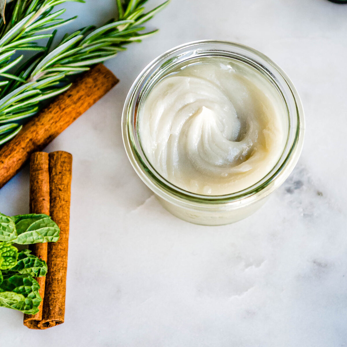Small jar of homemade vapor rub on a marbled countertop.