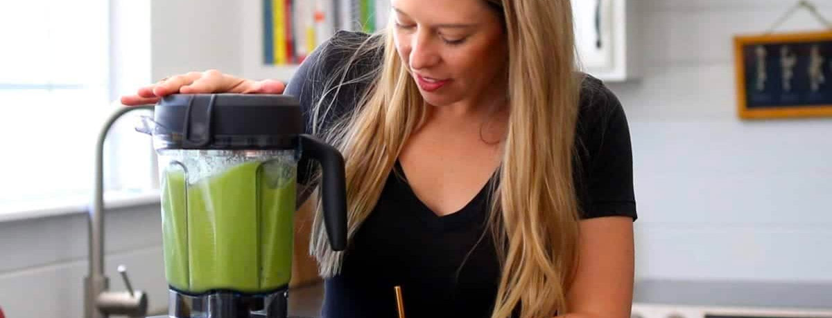 woman blending a green smoothie