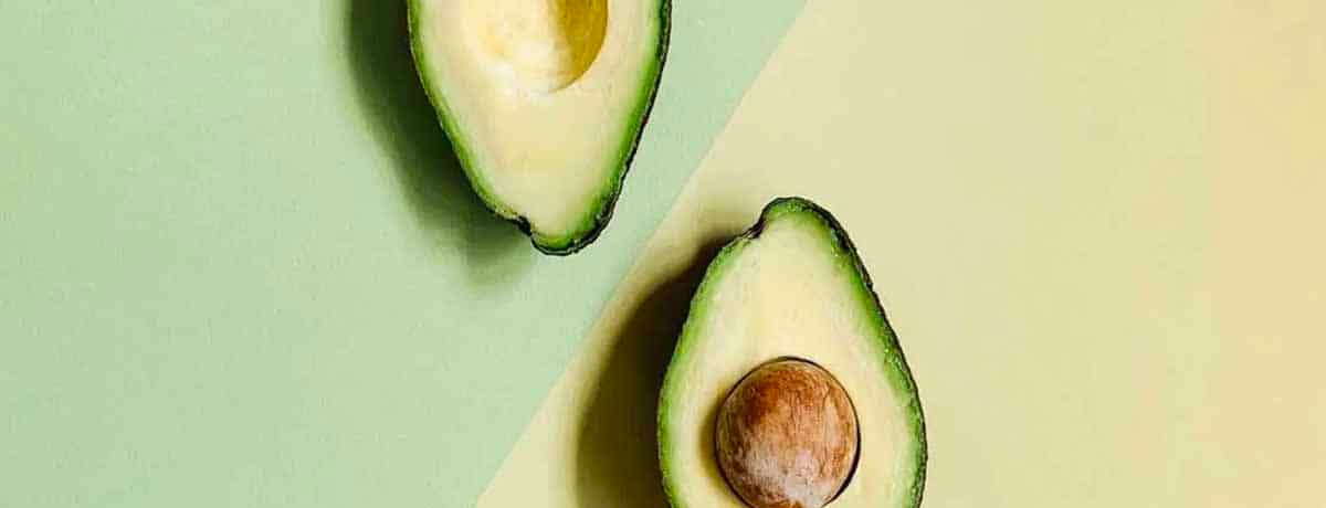 two halves of an avocado cut and laying face up on a table