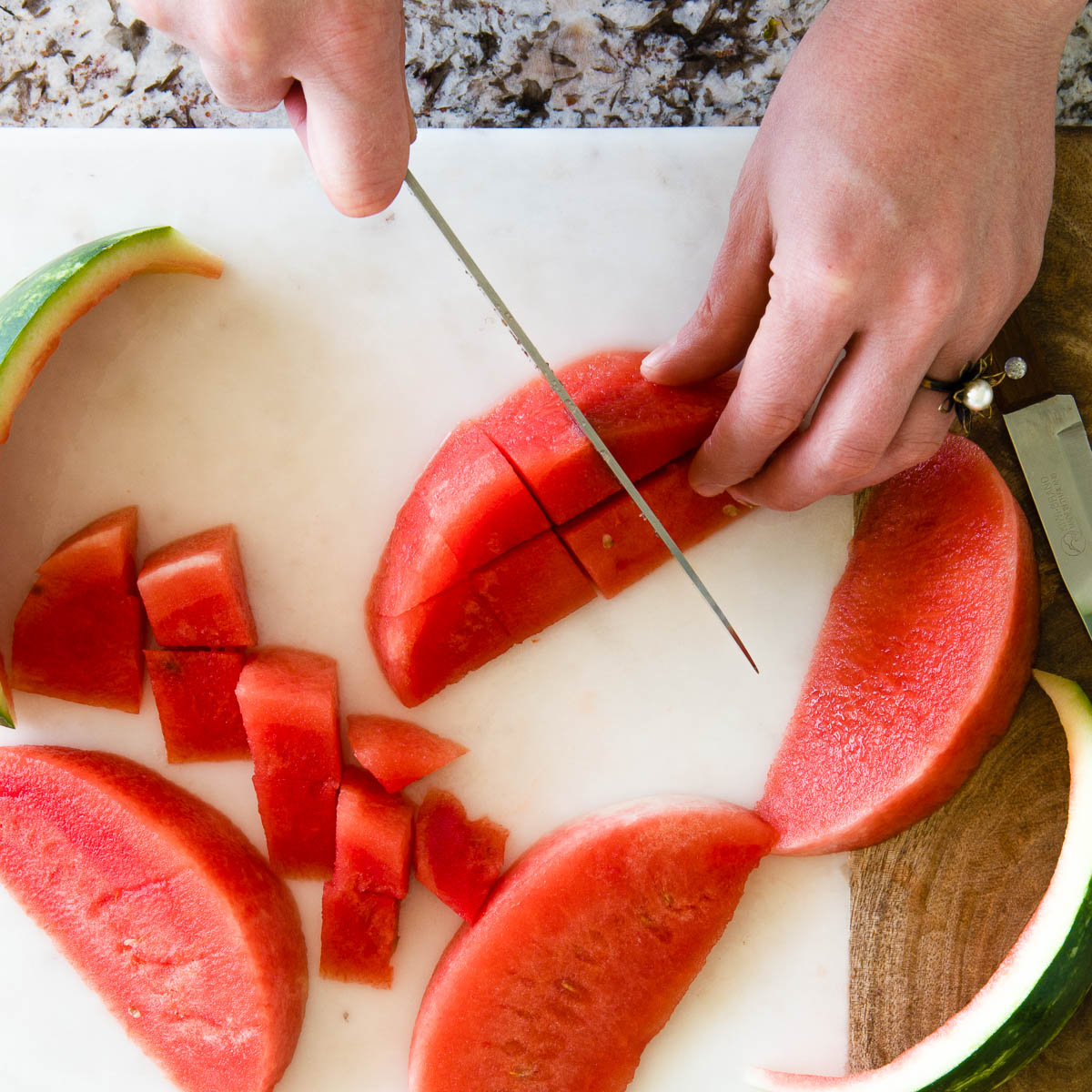 showing how to cut a melon by taking watermelon wedges into cubed pieces.