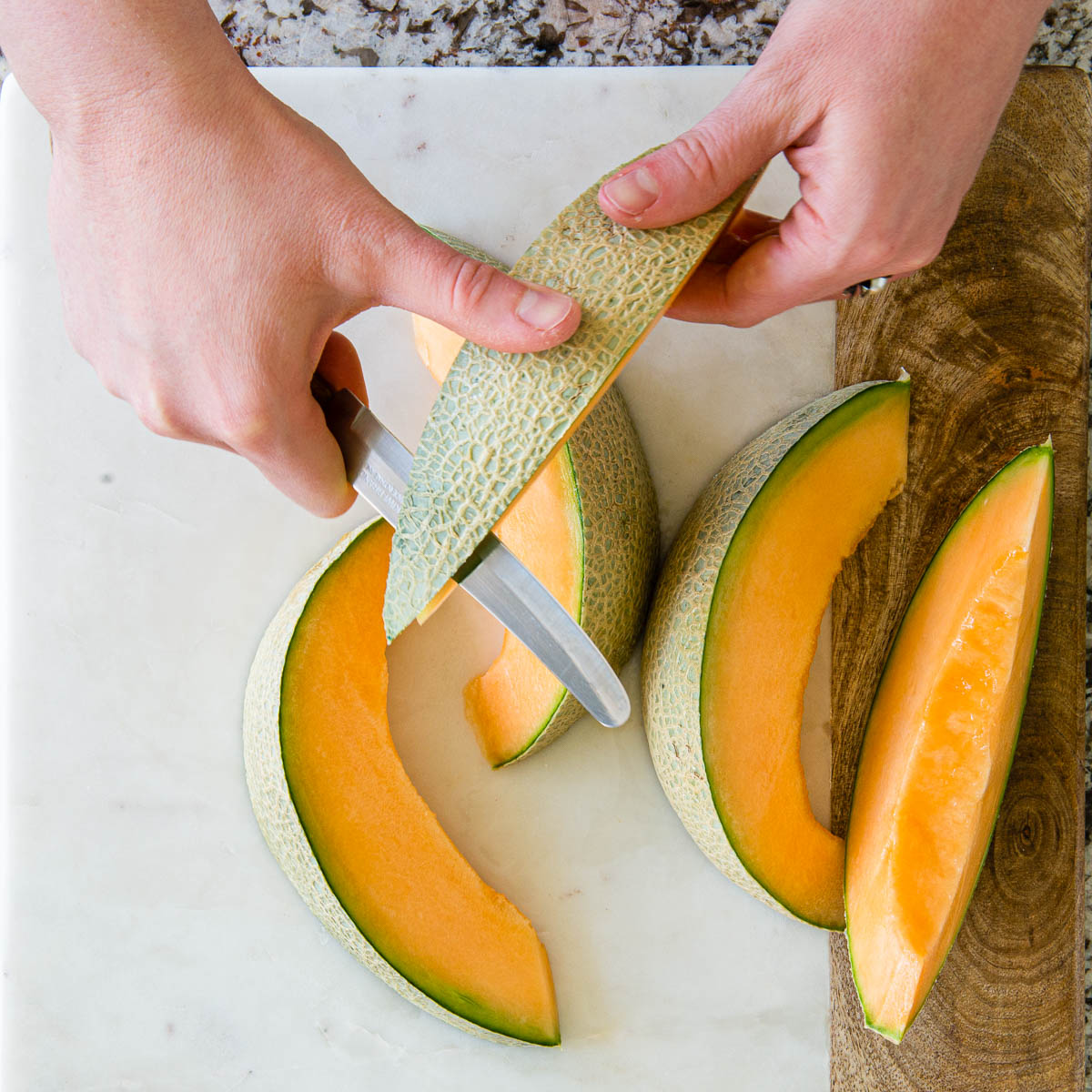slicing the rind away from the cantaloup wedges.