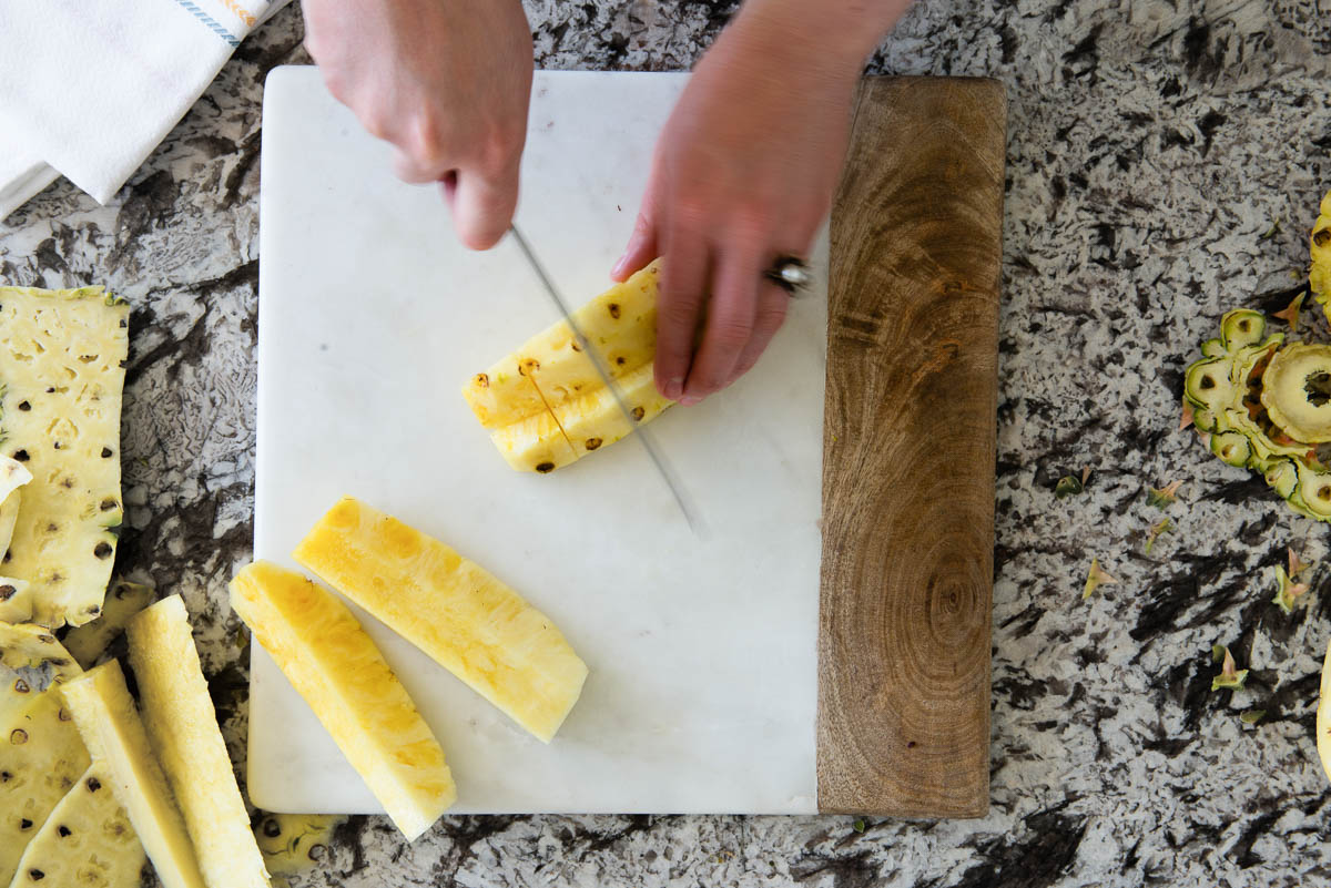 chopping up pieces of fruit on a marble cutting board.