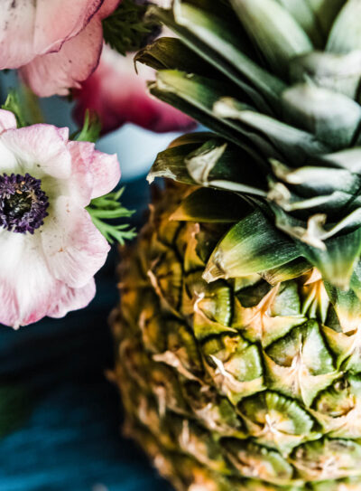 pink flowers next to a whole pineapple.