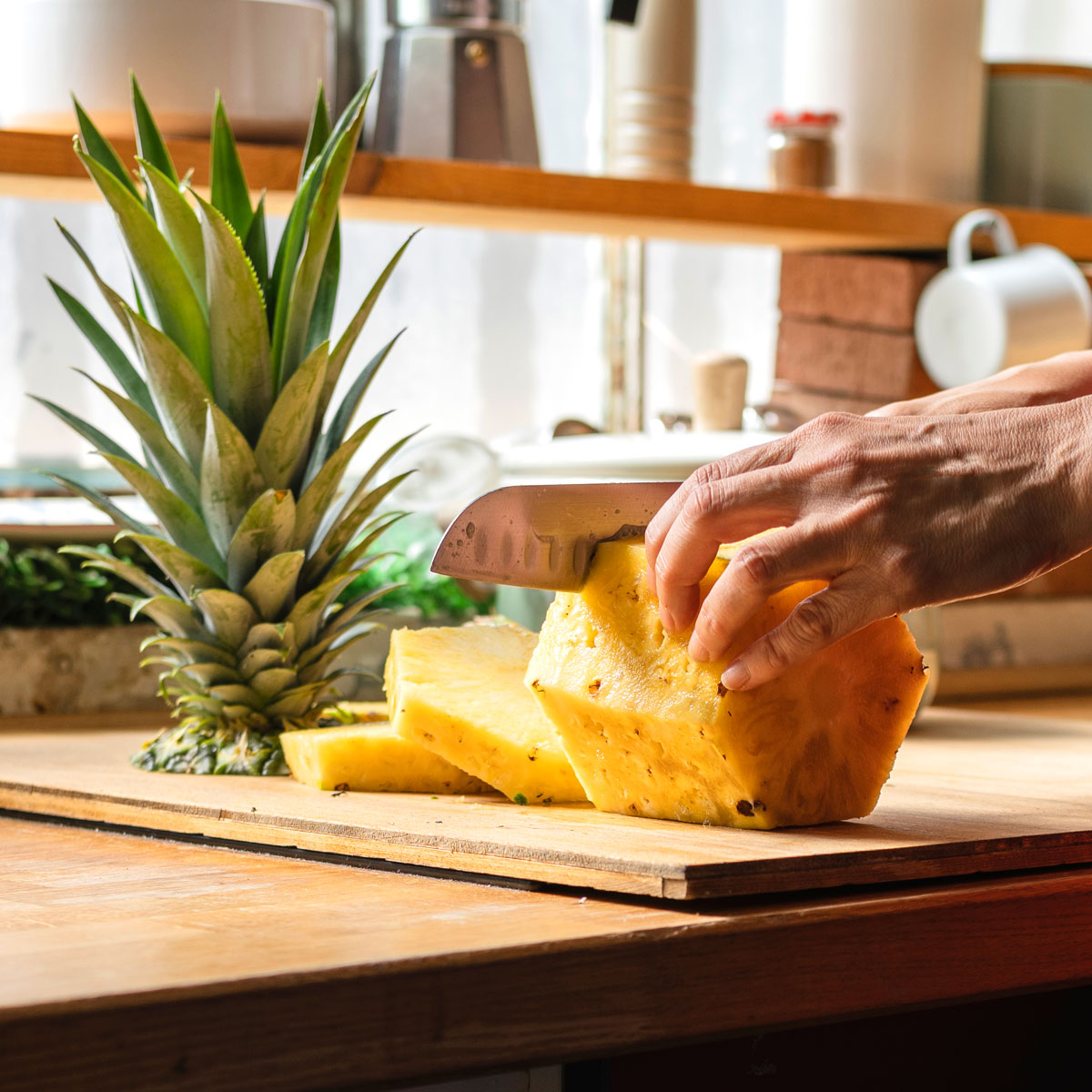 cutting pineapple with a knife on a cutting board.