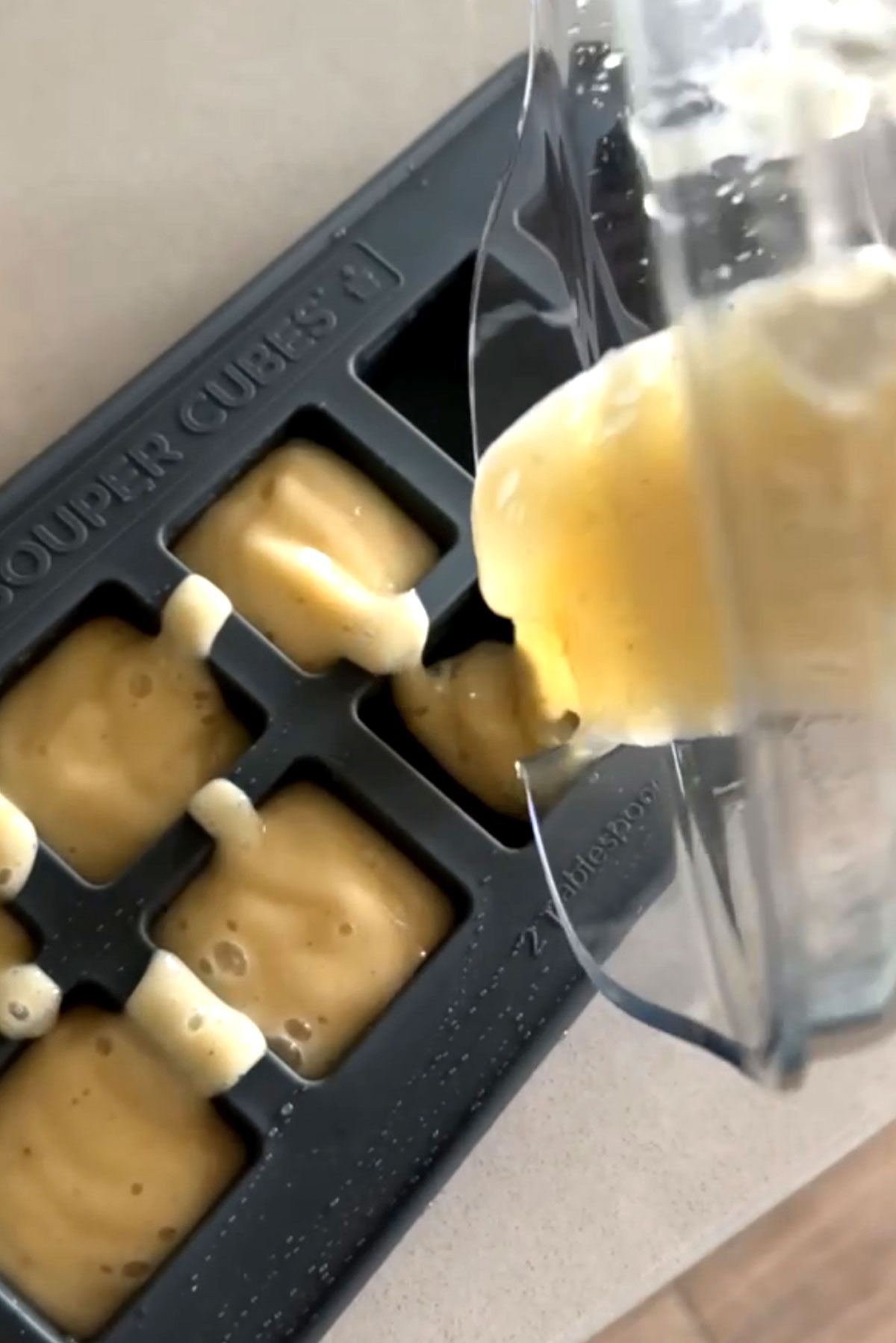 Banana puree poured into silicone ice cube trays to freeze