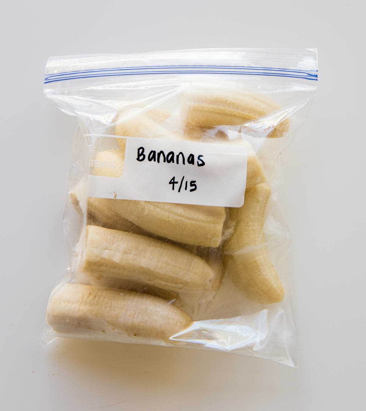 frozen, halved bananas in a freezer-safe plastic bag with the words Bananas 4/15 on it.