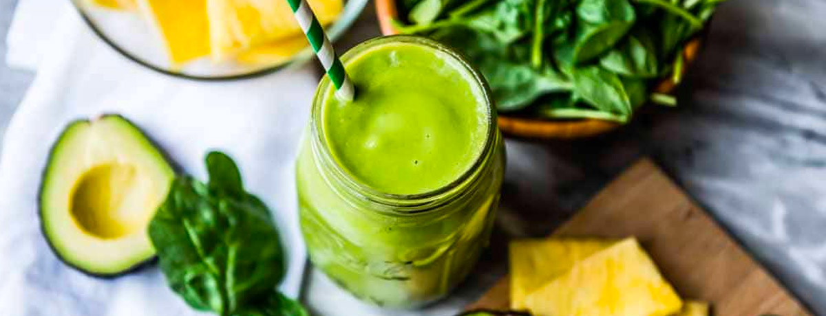 green smoothie with healthy ingredients next to it that help with clear skin