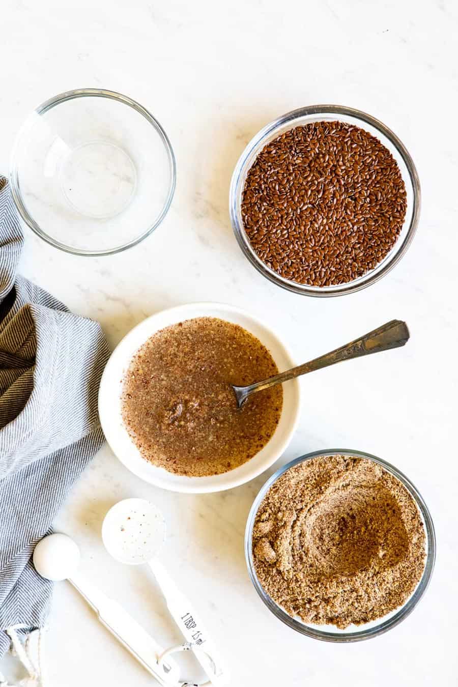 ground flax seeds in bowls with water and spoon to soak.