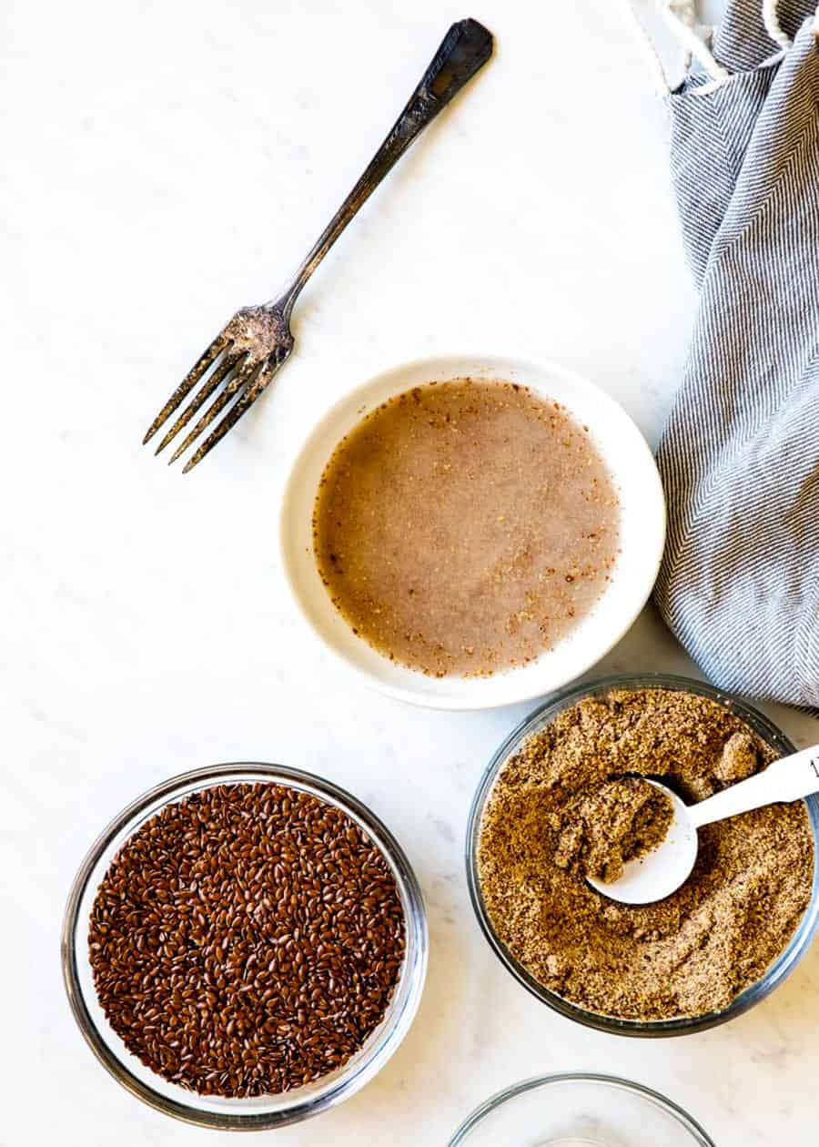 3 bowls, one of whole flax seeds, one of ground flaxseed and one of ground seeds soaking in water.