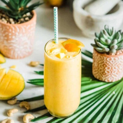 Mango smoothie recipe that's on table with fresh fruit and succulents for making smoothies.