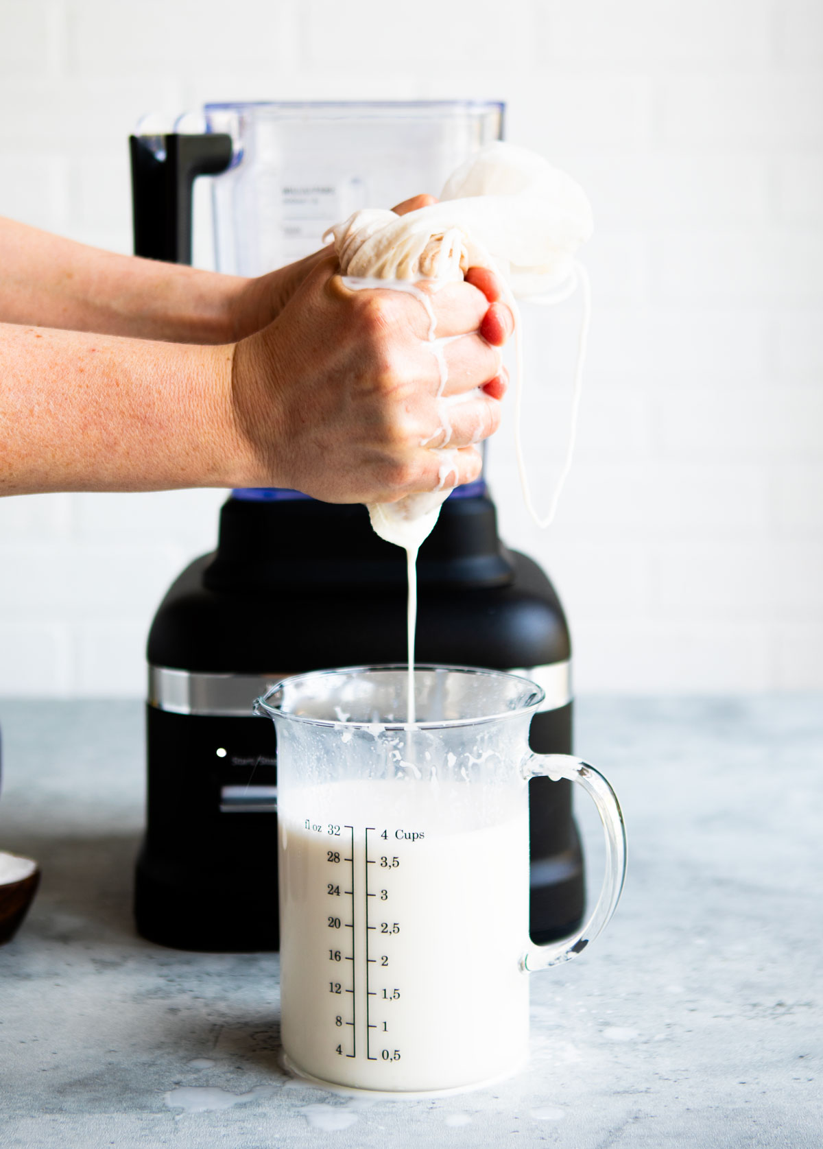 A person squeezing a nut milk bag to make homemade almond milk.