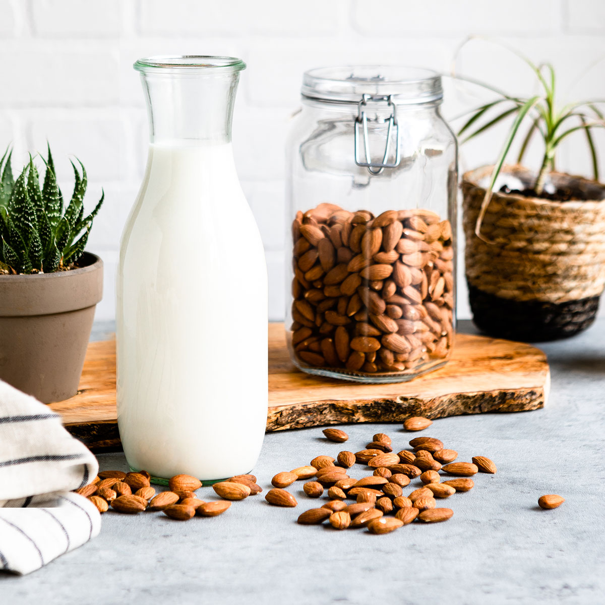 Almond milk in a glass carafe with jar of almonds in background.