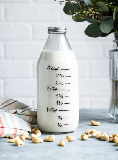 A glass jar filled with a cashew milk recipe, with measurement markings on the side.