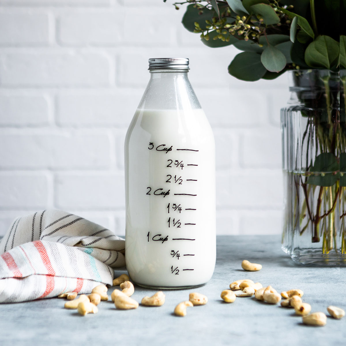 A glass jar filled with a cashew milk recipe, with measurement markings on the side.