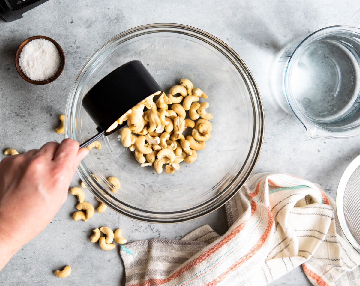 Pouring cashews into a glass bowl.