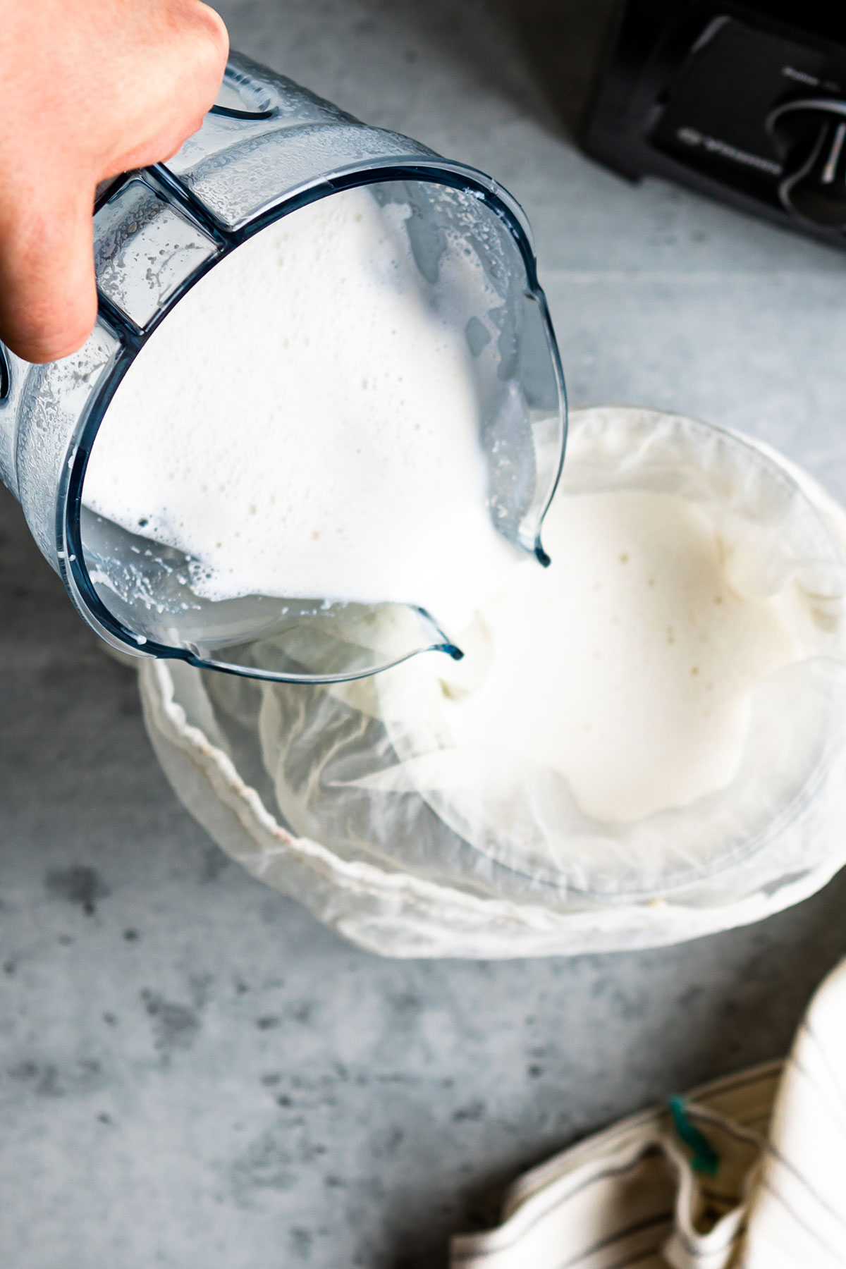 Pouring cashew milk into a nut milk bag.