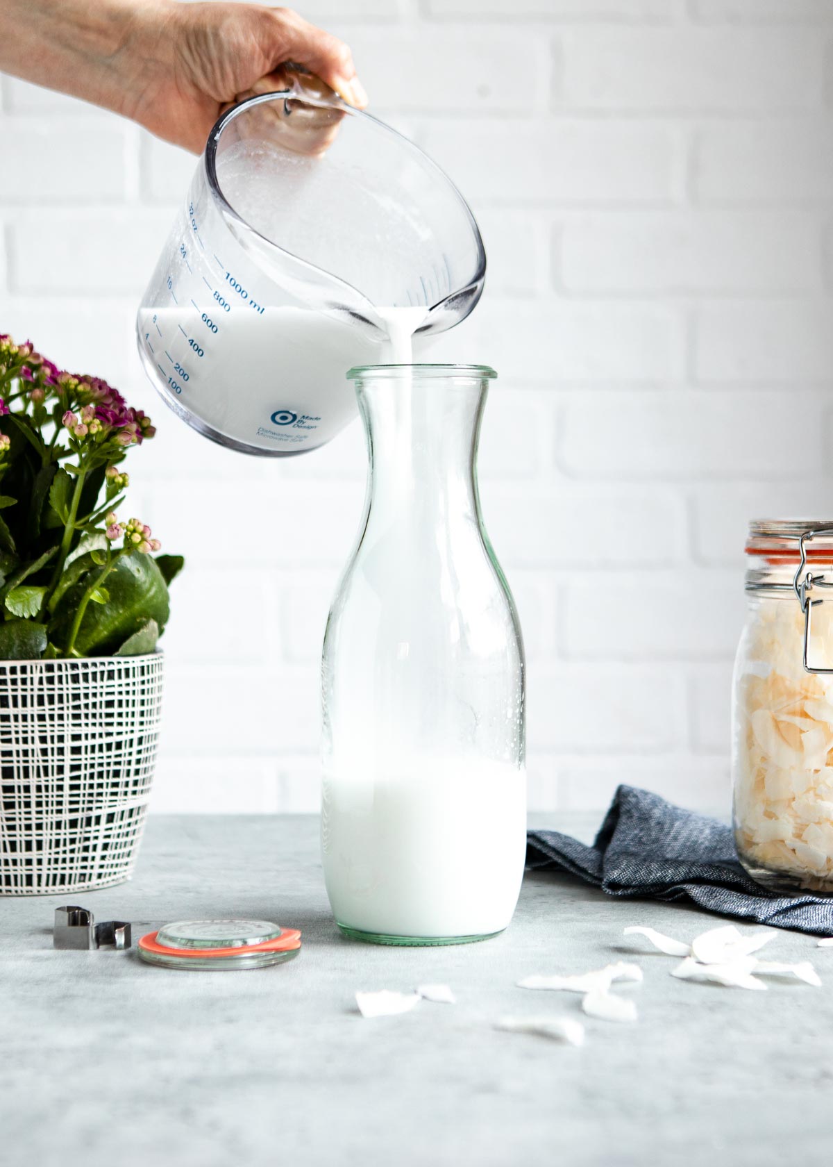pouring coconut milk into a glass pitcher.