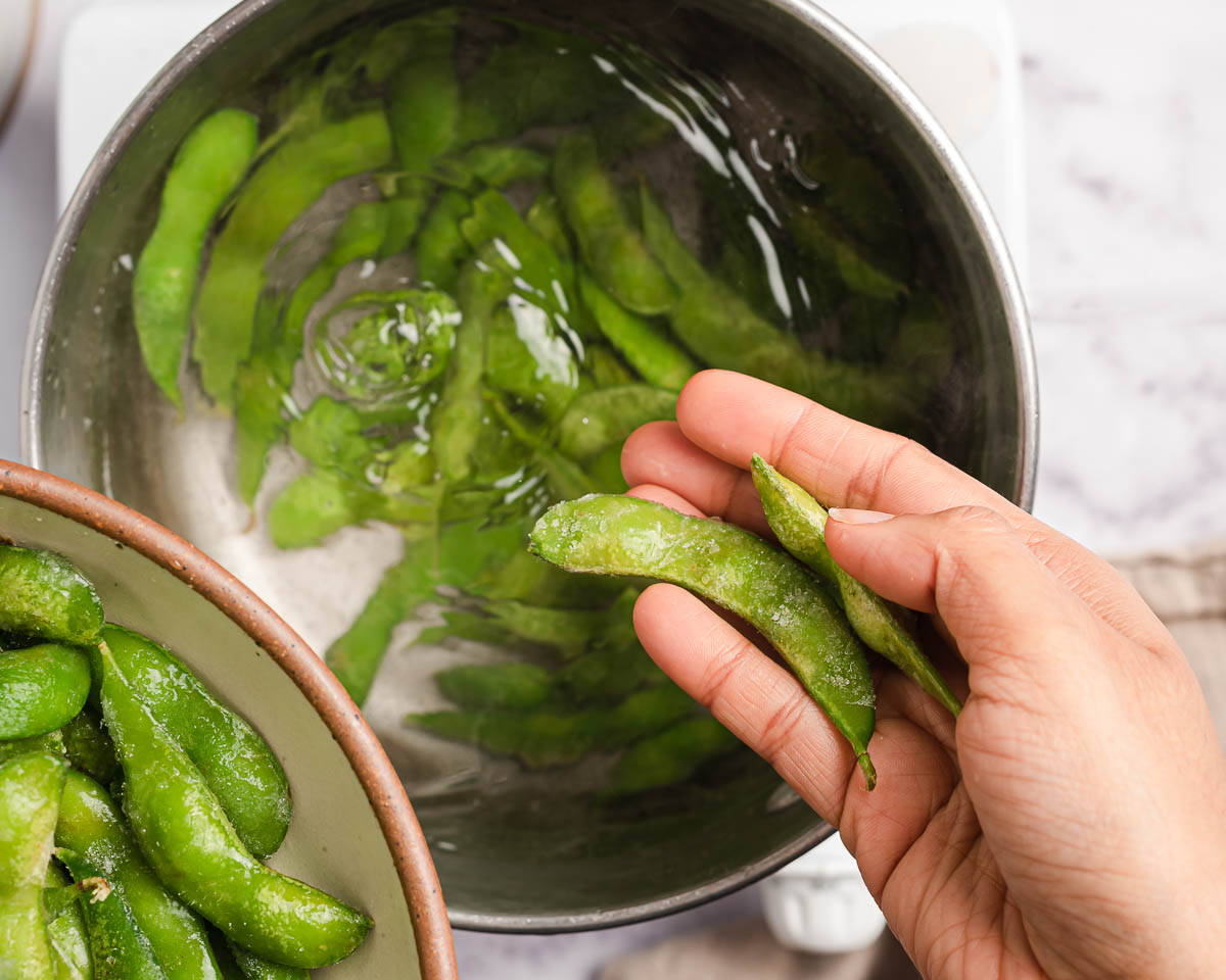 placing edamame into a sauce pan full of water.